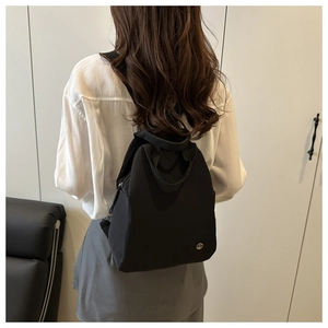 Detail view of lightweight black nylon backpack worn on back with minimalist design