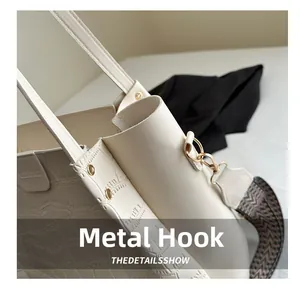Detail of white crocodile embossed tote bag with gold hardware hook and woven strap