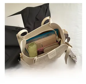 Interior view of large white tote bag with faux croc skin and wide patterned strap