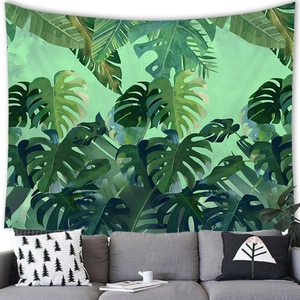 Detail of tropical green leaves tapestry hanging on white wall above a modern fabric sofa