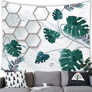 Detail of tropical monstera leaf wall tapestry over a grey sofa in a modern room