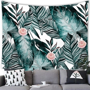 Tropical monstera leaf and pink rose tapestry hanging above a modern grey sofa