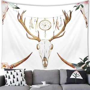 Detail of bohemian elk skull tapestry with dreamcatcher feathers above a grey sofa