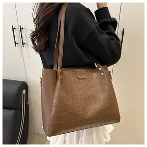 Close-up of brown crocodile embossed texture and metal rivet detail on large tote bag