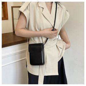 Vertical black faux leather crossbody phone bag shown being worn by a person