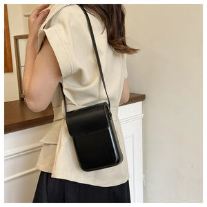 Mini bolso bandolera minimalista en cuero negro mostrado en modelo para ver la escala