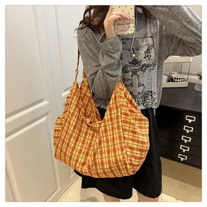 Gros plan sur un grand sac cabas en toile avec un motif à carreaux orange et rouge