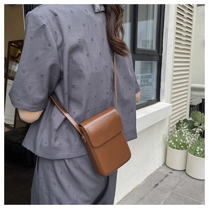 Chic brown faux leather crossbody phone bag shown in a lifestyle street setting