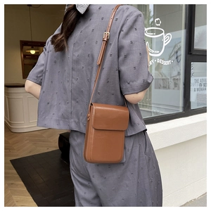 Close-up of brown polished leather mini crossbody phone bag with adjustable strap