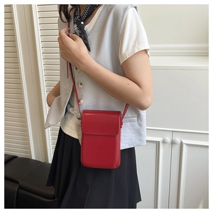 Detalle de un bolso bandolera rojo para móvil con diseño de solapa y correa fina
