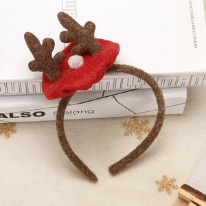 Serre-tête bois de renne de Noël avec peluche marron et pompon blanc sur des livres blancs