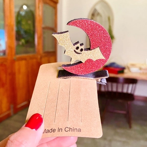 Creative Halloween hair clip with glittery red moon and golden bat on kraft card
