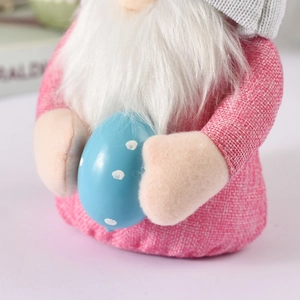 Dettaglio dello gnomo di Pasqua rosa con uovo blu a pois con trama a maglia e barba bianca