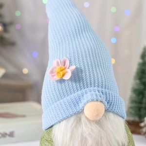 Dettaglio di uno gnomo pasquale con cappello in maglia azzurra e piccolo fiore rosa