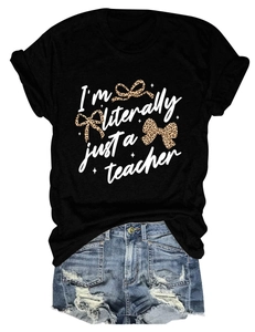 Close-up of I'm Literally Just a Teacher slogan with leopard bows on black cotton T-shirt