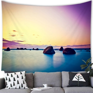 Detail of tropical sunset wall tapestry hanging above a modern sofa for home decor