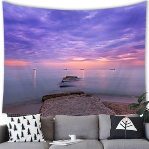 Detail of tropical sunset beach tapestry with ship and sea behind a modern grey sofa