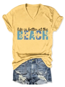 Detail of yellow V-neck tee with beach palm tree print and ripped denim shorts