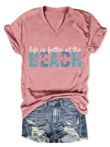 Detail of pink V-neck t-shirt with beach slogan and ripped denim shorts on white background