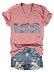 Detail view of pink V-neck T-shirt and distressed denim shorts with beach theme print