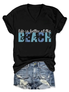 Flat lay of women's V-neck T-shirt and distressed denim shorts with beach lettering