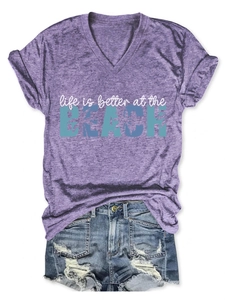 Detail of purple V-neck t-shirt with beach print paired with distressed denim shorts