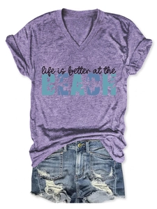 Flat lay of women's purple V-neck t-shirt and distressed denim shorts with palm tree print