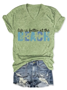 Flat lay of a green V-neck T-shirt with beach print and blue denim shorts with frayed hems