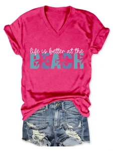 Flat lay of pink V-neck t-shirt with beach print and blue distressed denim shorts