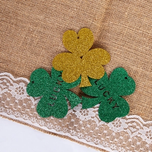 Close-up of glittery gold and green shamrock ornaments with Lucky cutout on burlap