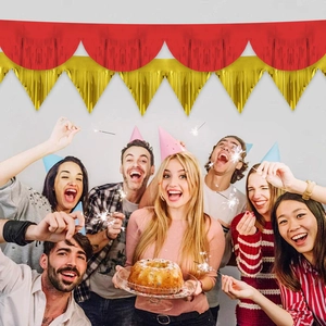 Birthday party decoration with red and gold metallic fringe banner over happy party crowd