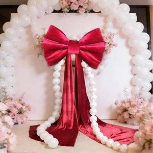 Macro shot of large burgundy velvet bow hanging as wedding backdrop with floral accents