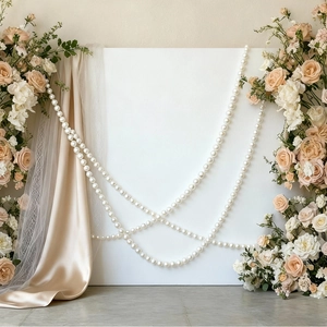 Close-up of elegant faux pearl strands hanging with champagne roses for wedding decor