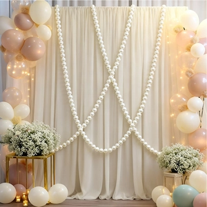 Close-up of elegant wedding backdrop with cream chiffon drapes and long pearl strand chains