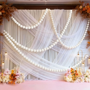 Faux pearl bead strands hanging against a fabric backdrop for wedding party decoration