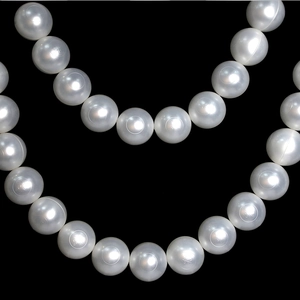 Macro shot of large white artificial pearls with elegant engraved patterns for DIY decor