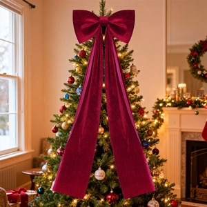 Deep red velvet Christmas tree topper bow with long streamers in a festive home setting