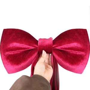 Detailed view of a large red velvet bow ornament featuring rich fiber texture