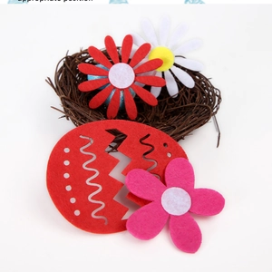 Détail d'un œuf de Pâques en feutre rouge et de petites fleurs colorées dans un nid de brindilles