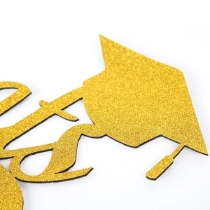 Detail of gold glitter cake topper with graduation cap and academic hat design