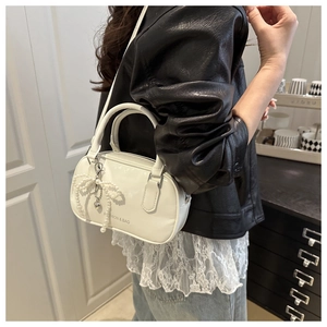 Close-up of white leather handbag with pearl bow pendant and heart charm detail