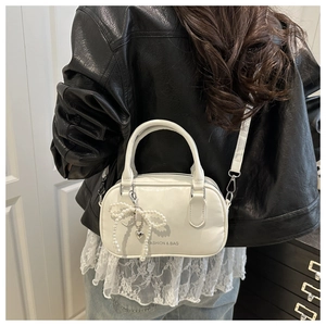 Detail of cream white mini Boston bag with pearl bow and silver heart pendant