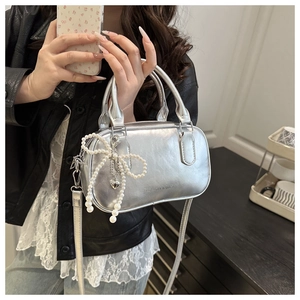 Close-up of silver metallic bowling bag with pearl bow charm and embossed fashion text