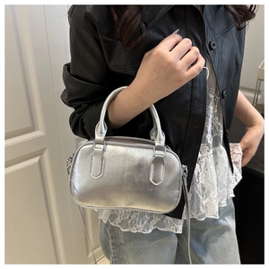 Detail of silver metallic mini boston bag showing embossed logo and shoulder strap