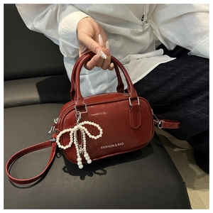 Close-up of deep red glossy handbag with pearl bow charm and Fashion & Bag lettering