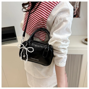 Detail of black bowling bag with pearl bow charm and silver-tone metal hardware