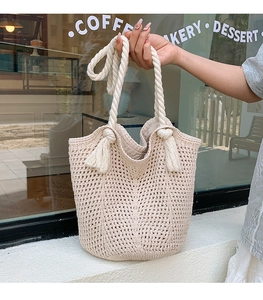 Close-up of cream crochet knit tote bag with thick rope handles and tassel side details