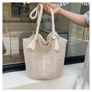Détail du sac fourre-tout beige au crochet avec poignées en corde et pompons