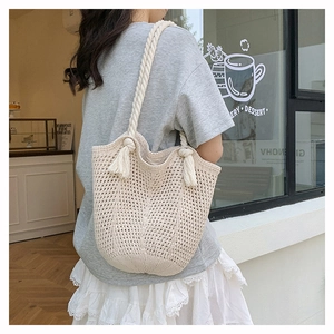 Detail of crochet tote bag with mesh texture and tassel drawstring in cream white