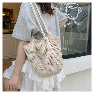 Detail of the cotton crochet weave texture and long fringe on the off-white beach tote bag